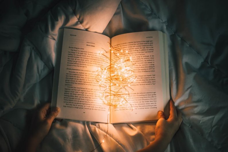 Story - person holding string lights on opened book