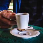 Consistency - person holding white ceramic mug on saucer
