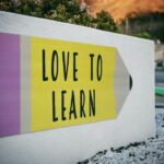 Skills - love to learn pencil signage on wall near walking man