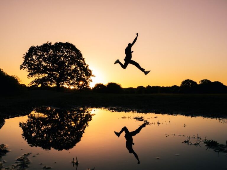 Action - silhouette photo of man jumping on body of water during golden hour