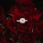 Engagement - silver-colored ring on top of red roses